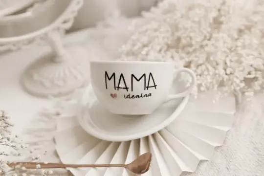 Biała filiżanka z napisem "Mama idealna" i serduszkiem, idealny prezent na Dzień Matki.
